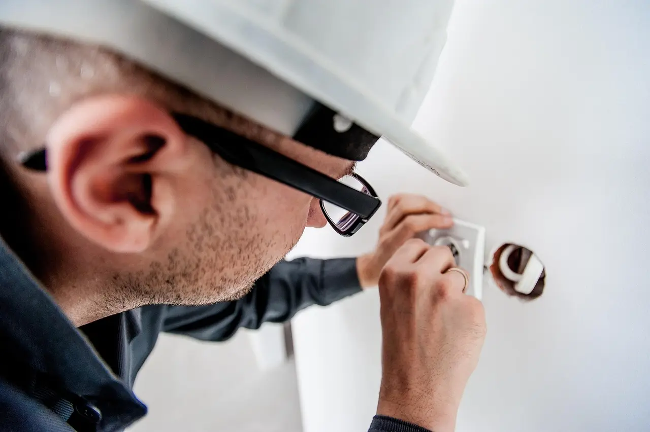 Électricien contrôlant la barrette de terre et le conducteur de terre d'un tableau électrique dans une maison ancienne