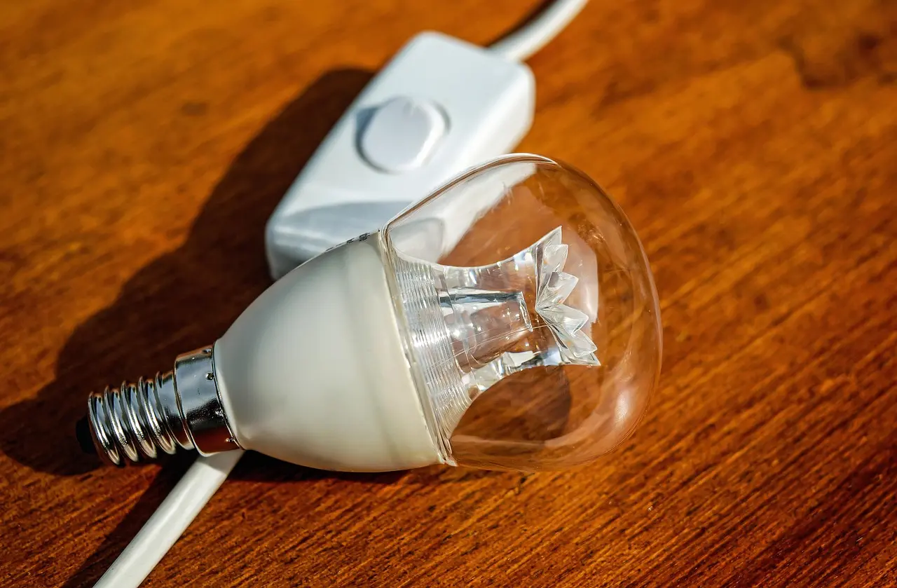 Électricien installant un micromodule connecté dans la boîte d'encastrement derrière un interrupteur mural déposé