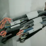 Couronne de câble R2V à gaine noire posée à côté de fils H07V-U de couleurs différentes sur un établi d'électricien