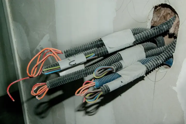 Couronne de câble R2V à gaine noire posée à côté de fils H07V-U de couleurs différentes sur un établi d'électricien