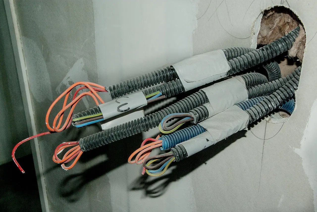 Couronne de câble R2V à gaine noire posée à côté de fils H07V-U de couleurs différentes sur un établi d'électricien
