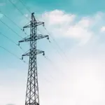 Électricien mesurant la tension en bout d'une longue ligne de câble alimentant un bâtiment annexe