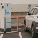 Électricien installant une borne de recharge pour véhicule électrique dans le parking collectif d'un immeuble en copropriété