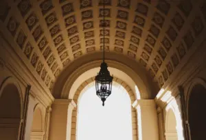 Électricien réglant un détecteur de mouvement encastré au plafond d'un couloir d'habitation