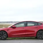 Électricien raccordant une borne de recharge murale pour véhicule électrique dans un garage de maison individuelle
