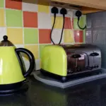 Cuisine en rénovation avec prises encastrées derrière l'électroménager et tableau électrique ouvert montrant les disjoncteurs 20 A