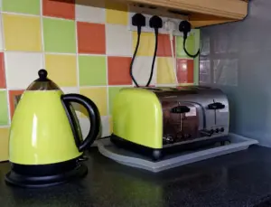 Cuisine en rénovation avec prises encastrées derrière l'électroménager et tableau électrique ouvert montrant les disjoncteurs 20 A